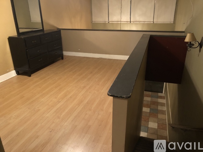 A room with a wooden floor and a black dresser.