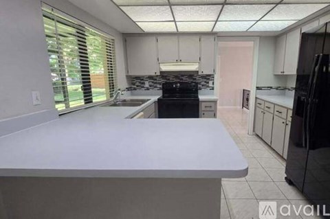 A kitchen with white cabinets and a black stove top oven.