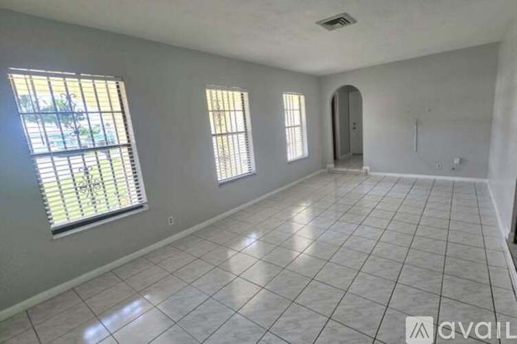 A spacious room with tile flooring and two windows.