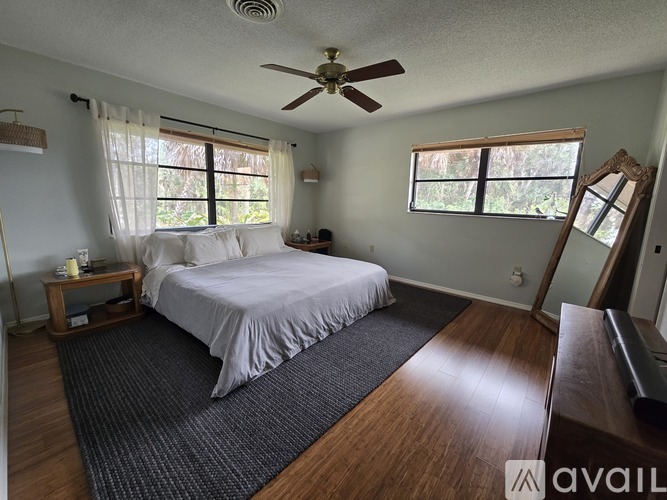 A bedroom with a bed, a ceiling fan, and a window with blinds.