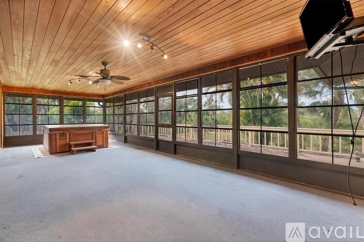 A spacious room with a wooden ceiling and a large window overlooking a balcony.