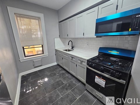 A kitchen with a black stove top oven and a window with blinds.