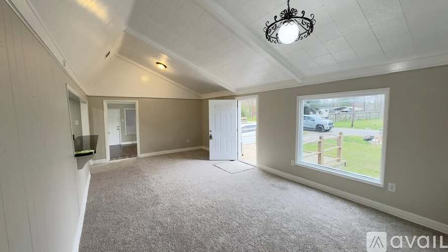 A room with a carpeted floor and a window showing a parking lot outside.