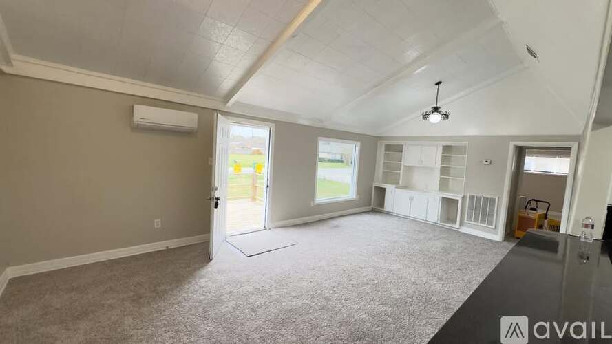 A spacious room with a carpeted floor and a ceiling fan.