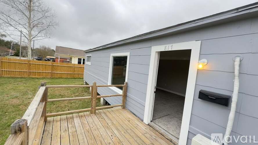 A grey building with a white door and a wooden deck.