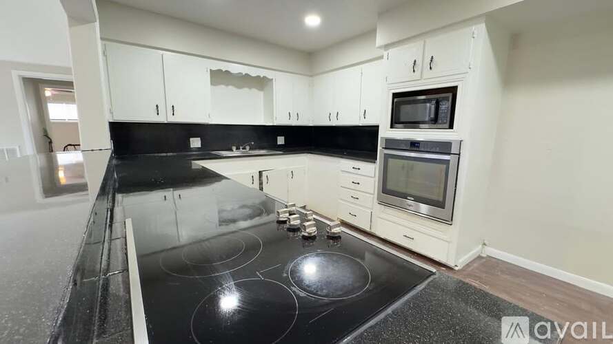 A modern kitchen with a black countertop and stove.