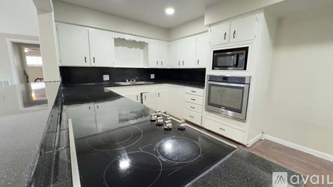 A modern kitchen with a black countertop and stove.