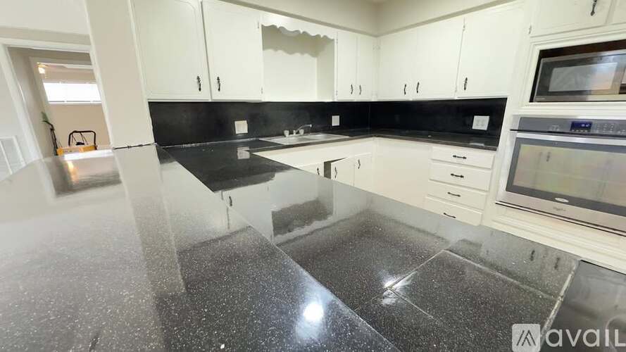 A kitchen with black countertops and white cabinets.