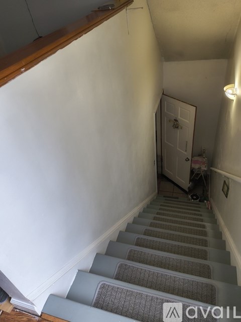 A staircase with a carpeted runner and wooden handrail.