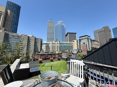 A cityscape with a clear blue sky and a building with a glass facade in the center.