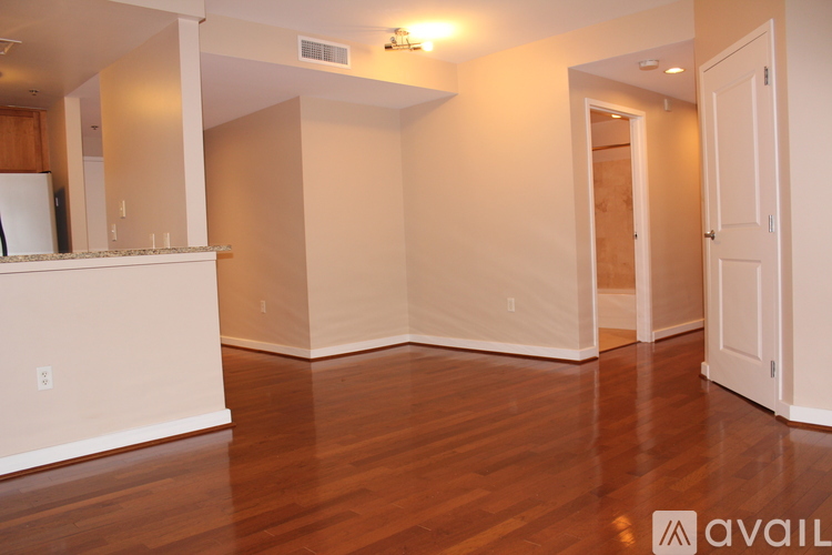 A spacious living room with hardwood floors and white walls.