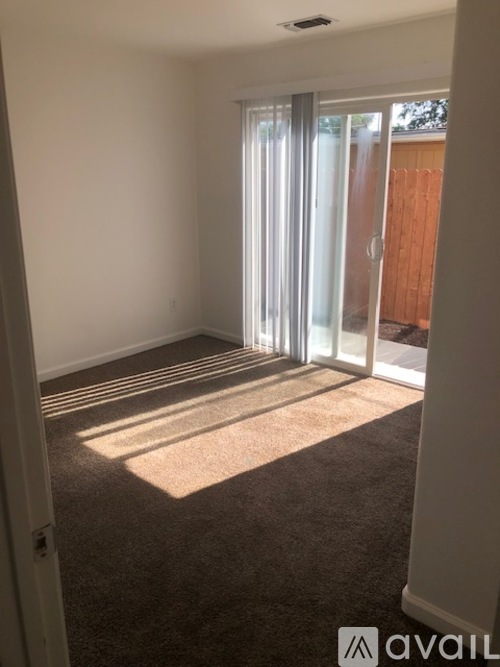 A room with a carpeted floor and a sliding glass door.
