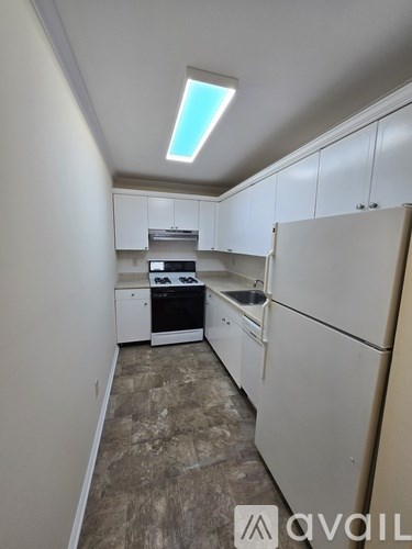 A kitchen with white cabinets and a tiled floor.