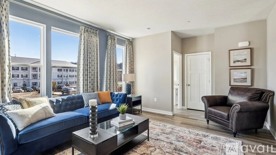 A living room with a blue couch and a glass coffee table.