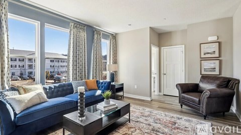 A living room with a blue couch and a glass coffee table.