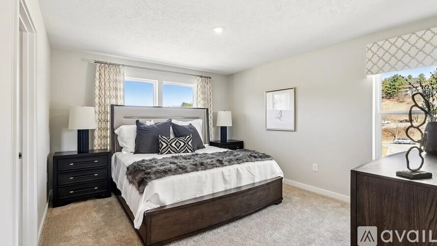 A bedroom with a large bed, two lamps, and a framed picture on the wall.
