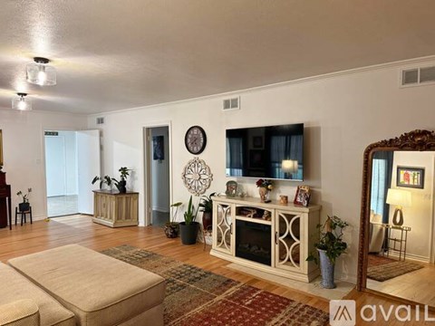 A living room with a white fireplace and a rug on the floor.