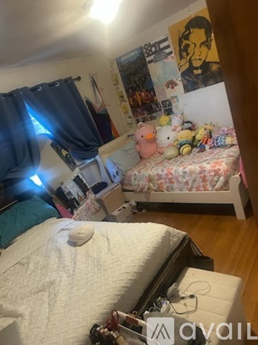 A messy bedroom with a bed, a desk, and a wall covered in posters and pictures.