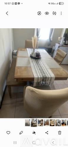 A dining table with a striped runner and a white vase with dried flowers on it.