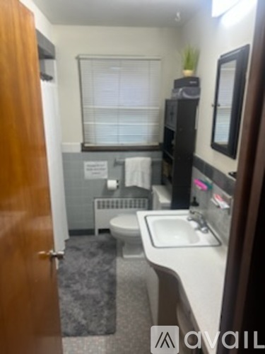A bathroom with a toilet, sink, and mirror.