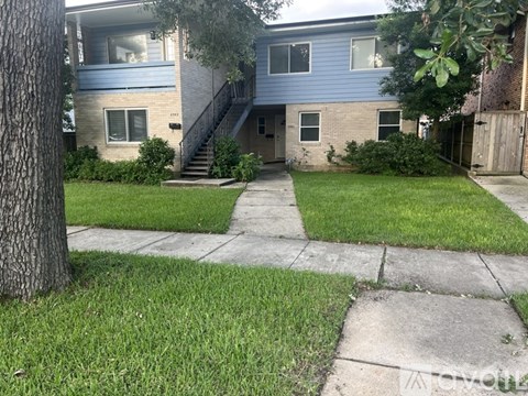 A blue house with a tree in front.