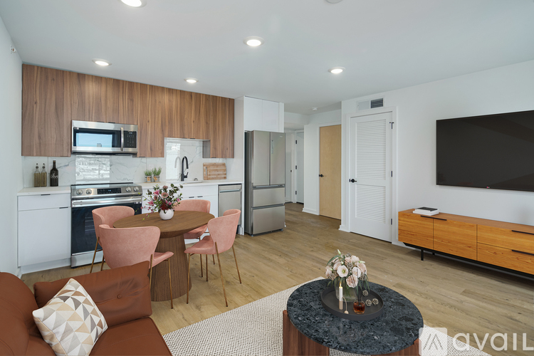 A modern living room with a brown sofa, a coffee table, and a kitchen area in the background.