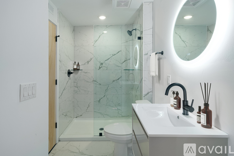 A bathroom with a marble wall and a round mirror.