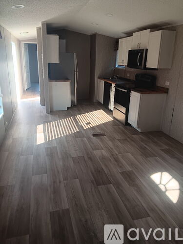 A kitchen with wooden floors and white cabinets.