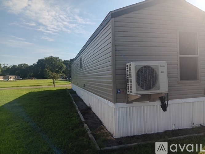 A house with a grey siding and a white air conditioning unit on the side.