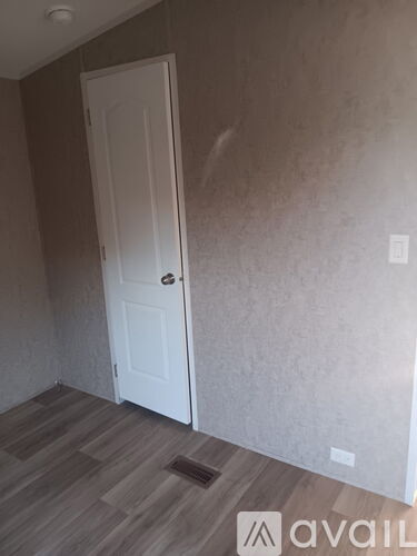 A room with a white door and wooden flooring.
