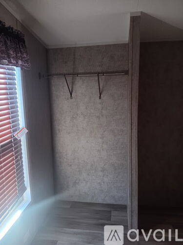 A room with a wall hook and a window with blinds.