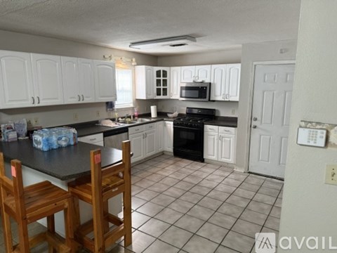 A kitchen with white cabinets and black appliances.