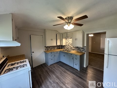 A kitchen with a white stove and a fan on the ceiling.