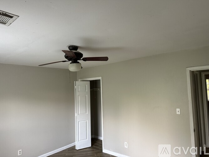 A room with a ceiling fan and a door.