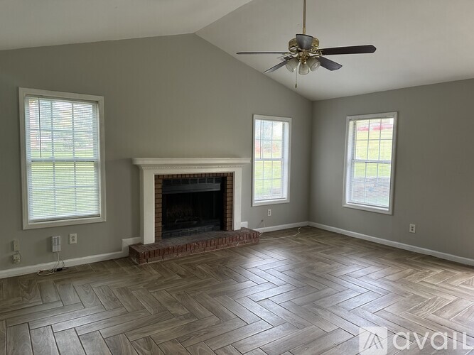 A living room with a fireplace and a ceiling fan.