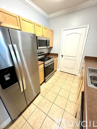 A kitchen with a stainless steel refrigerator and wooden cabinets.