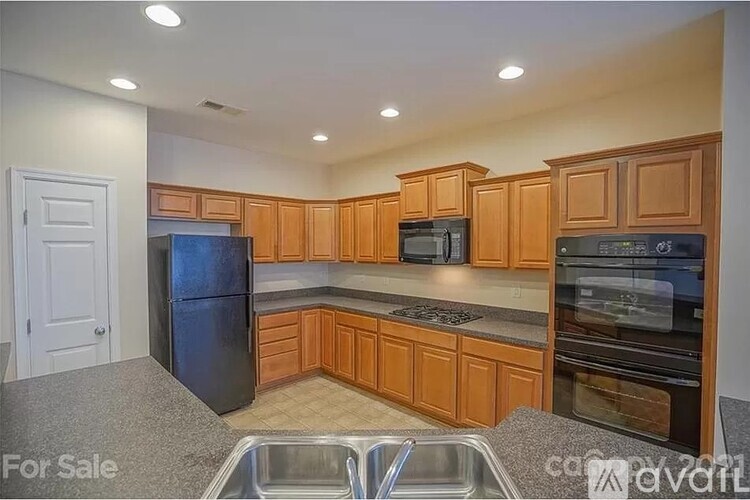 A kitchen with wooden cabinets and a black refrigerator is for sale.