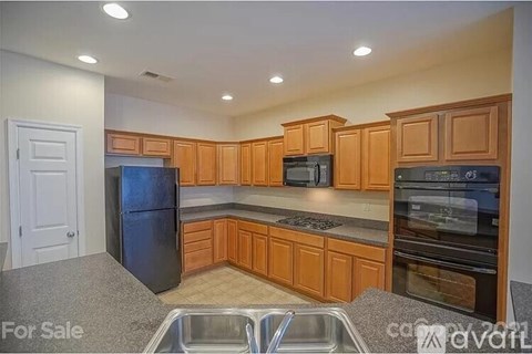 A kitchen with wooden cabinets and a black refrigerator is for sale.
