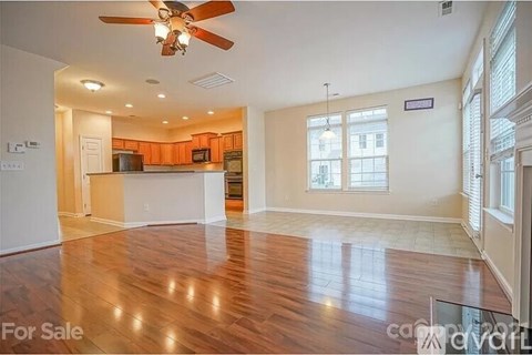 A spacious room with wood flooring and a ceiling fan is for sale.