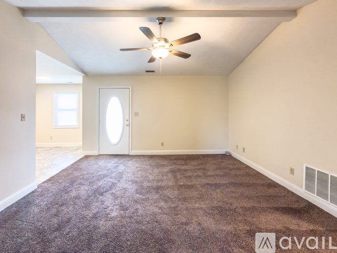 A room with a ceiling fan and carpeted floor.