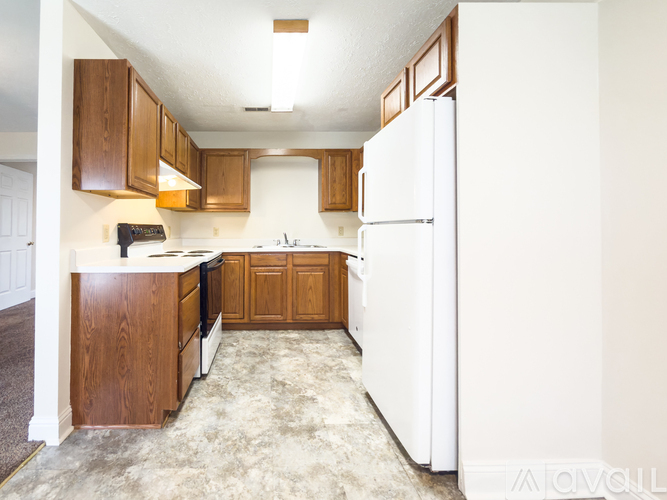 A kitchen with white appliances and wooden cabinets.