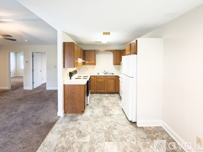 A kitchen with white appliances and wooden cabinets.