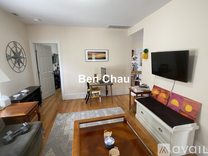 A living room with a couch, coffee table, and a flat screen TV mounted on the wall.