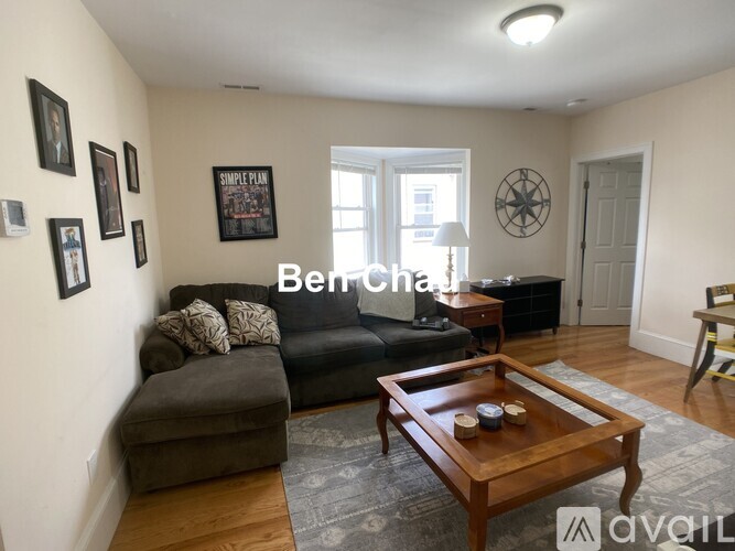 A living room with a sofa, a coffee table, and a wall with pictures and a clock.