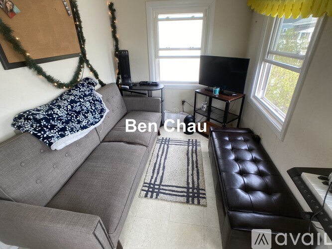 A living room with a grey sofa and a black leather ottoman.