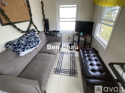 A living room with a grey sofa and a black leather ottoman.