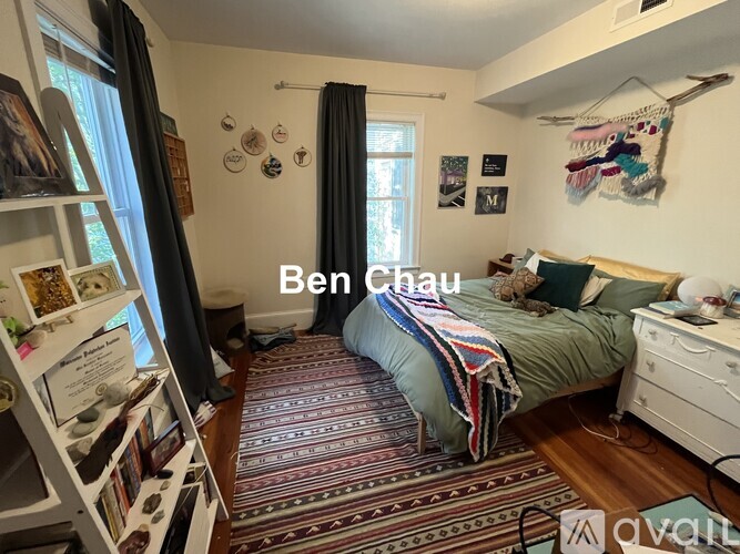 A bedroom with a bed, a window with curtains, and a rug on the floor.