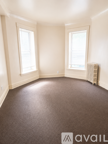 A room with a carpeted floor and two windows.