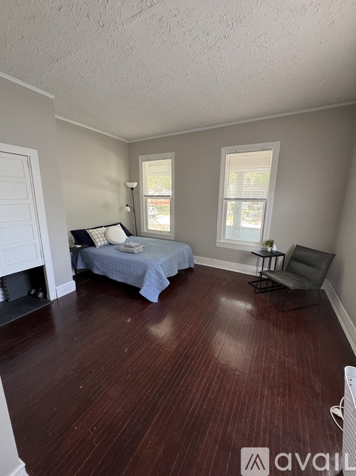 A bedroom with a bed, chair, and window.