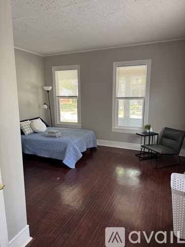 A bedroom with a bed, chair, and lamp.